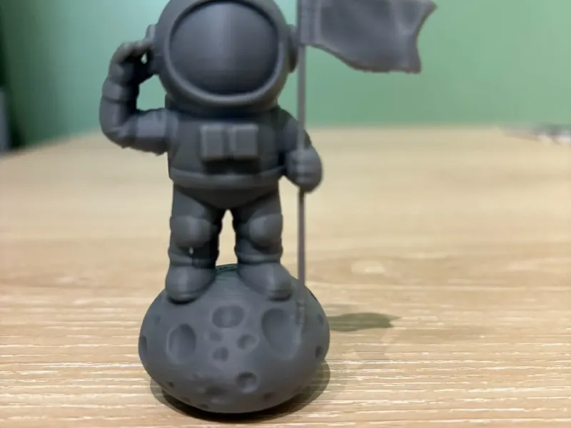 Mini astronauta sulla roccia con bandiera