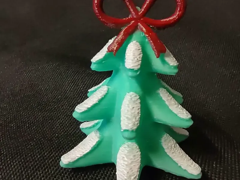 Árbol de Navidad nevado coronado con una figurilla de lazo