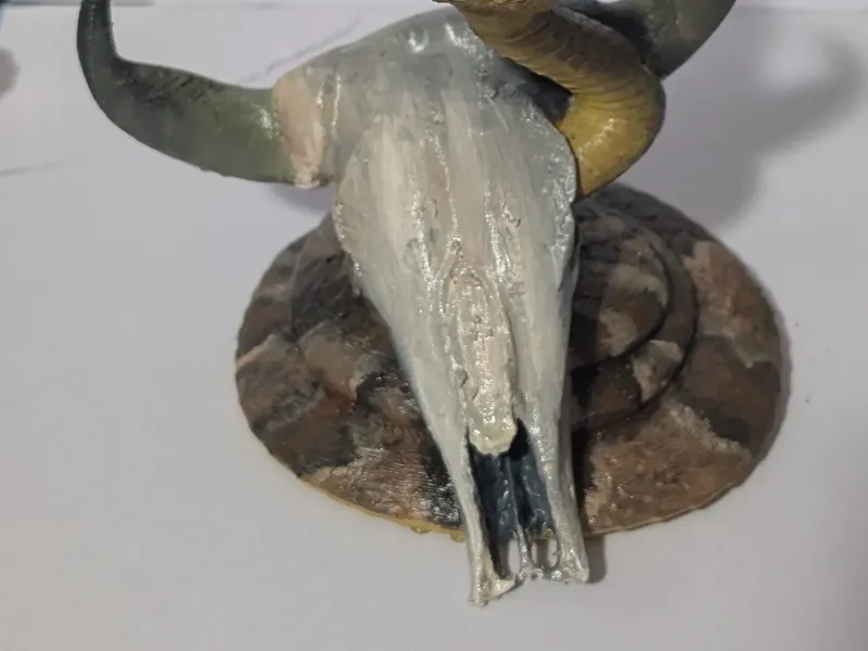 Cráneo de toro con una serpiente (boca abierta)