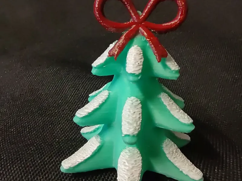 Snowy Christmas Tree topped with a Bow Figurine