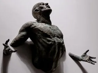 Escultura hombre emerge de la pared